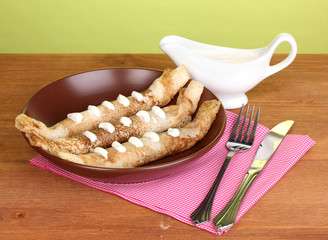 Stack of tasty pancakes on wooden table on green background