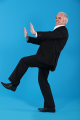 middle-aged man in suit pushing invisible furniture