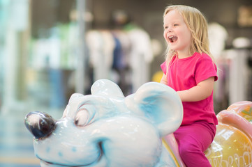 Adorable baby ride on carousel in mall