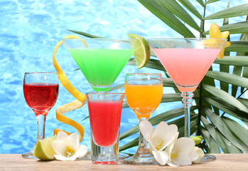 exotic cocktails and flowers on table on blue sea background