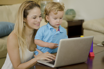 Cute young mother showing her son something in a laptop