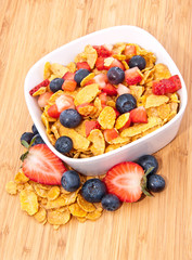 Cornflakes with fruits on wood