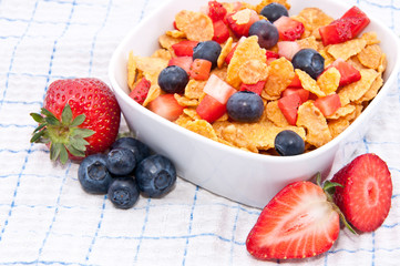 Cornflakes with fresh fruits on a tablecloth