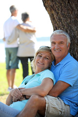 Mature couple leaning on tree trunk