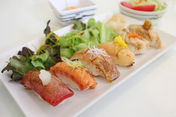 Mix of grilled fish with Japanese rice (Sushi) with salad