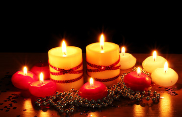 Beautiful candles and decor on wooden table on black background