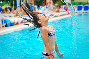 Young happy girl jumping out of the water of piscine