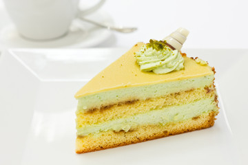 Slice of pistachio sponge cake with fondant icing and coffee
