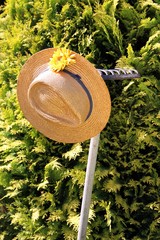 Strohhut mit rostiger Harke im Garten