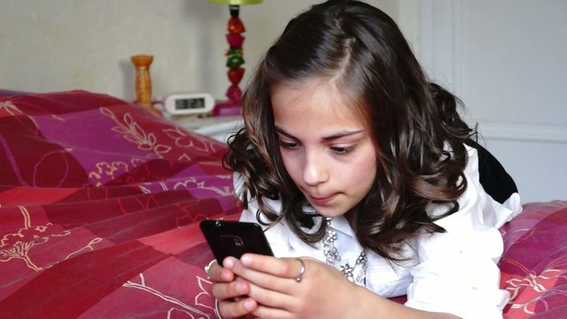 pr&eacute;ado avec son portable sur son lit