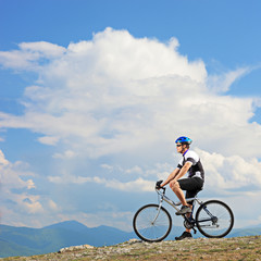 A man posing with a mountain bike on a ridge