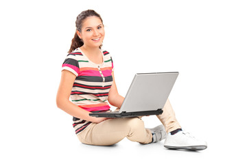 A smiling teenager doing her homework on a laptop
