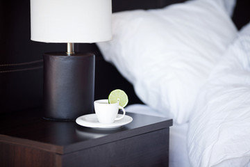 Fototapeta na wymiar łóżko z poduszką, kubek herbaty na stoliku i lampy