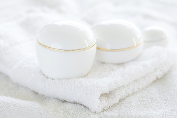 cosmetic containers lying on white towel
