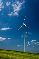 Obraz premium Wind Turbines on green field with blue sky