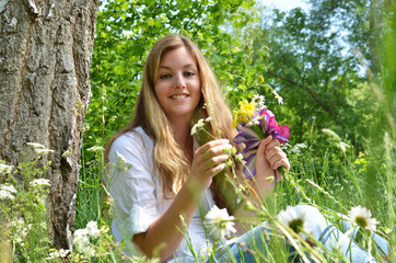 Young, happy woman relaxing outside on a meadow under a tree