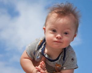 Baby boy with Down Syndrome boy being held up toward sky