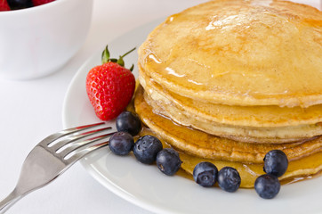 Pile of golden pancakes topped with honey
