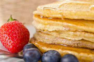 Pile of golden pancakes topped with honey