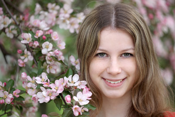 Fototapeta premium Portrait of the girl against a blossoming apple-tree