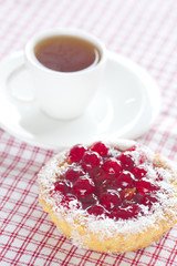 beautiful cake with berries and tea on plaid fabric