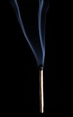 Burned match over a black background, with smoke