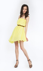 Trendy young woman in yellow dress smiling on white background
