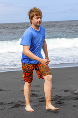 Fototapeta na wymiar boy has fun at the black volcanic beach