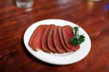 Slices of basturma on white plate