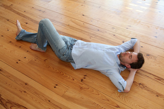 Young man relaxing on wooden floor in apartment