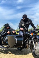 Fototapeta na wymiar Dwóch uzbrojonych mężczyzn motocykl z wózkiem bocznym