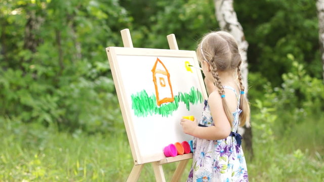 Little girl drawing a dream home in the park - 1