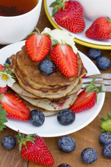 A stack of pancakes with a creamy fresh summer berries
