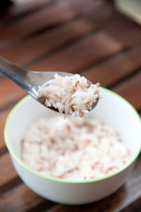 White and brown steamed rice with spoon in white round bowl
