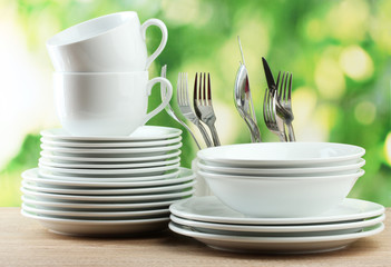 Clean dishes on wooden table on green background