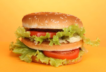 Big and tasty hamburger on yellow background