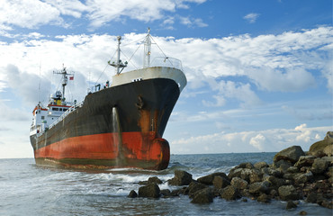 Cargo ship run aground on rocky shore shore