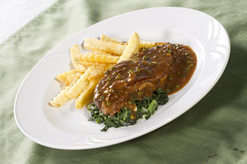beef steak with brown sauce spinach and french fries