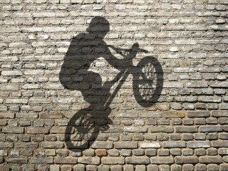 ombre de d'homme en BMX sur mur de briques
