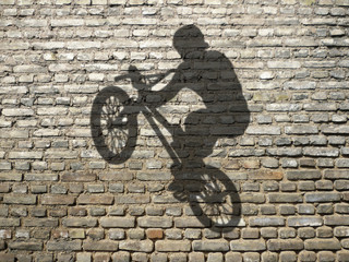 ombre d'homme en BMX sur mur de briques