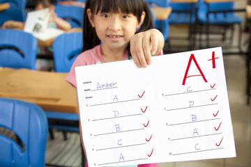 smiling little girl showing exam paper