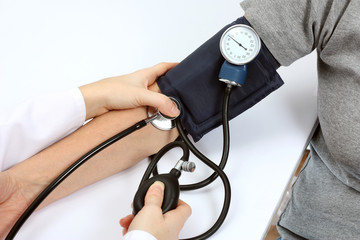 Doctor checking blood pressure with stethoscope and sphygmomanom