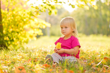 Adorable baby sit on grass with leaf under trees shadow on sunse