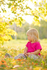 Adorable baby sit on grass with leaf under trees shadow on sunse