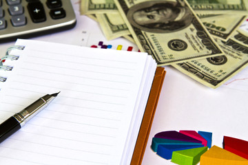 Pen ,calculator and dollars on financial Graphs