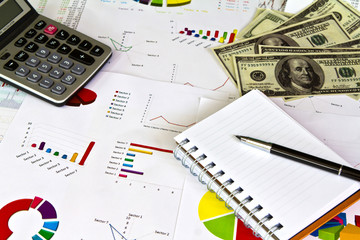 Pen ,calculator and dollars on financial Graphs