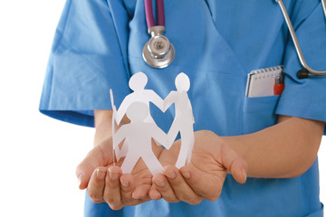 A female doctor holding paper people, focus on the hands