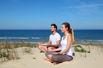 Fototapeta na wymiar Couple doing yoga exercices on a sandy beach