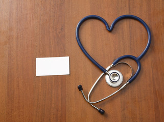 A stethoscope in a shape of heart with a blank lying on a desk