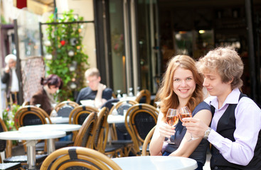 Beautiful couple having a date in a cafe and drinking pink wine